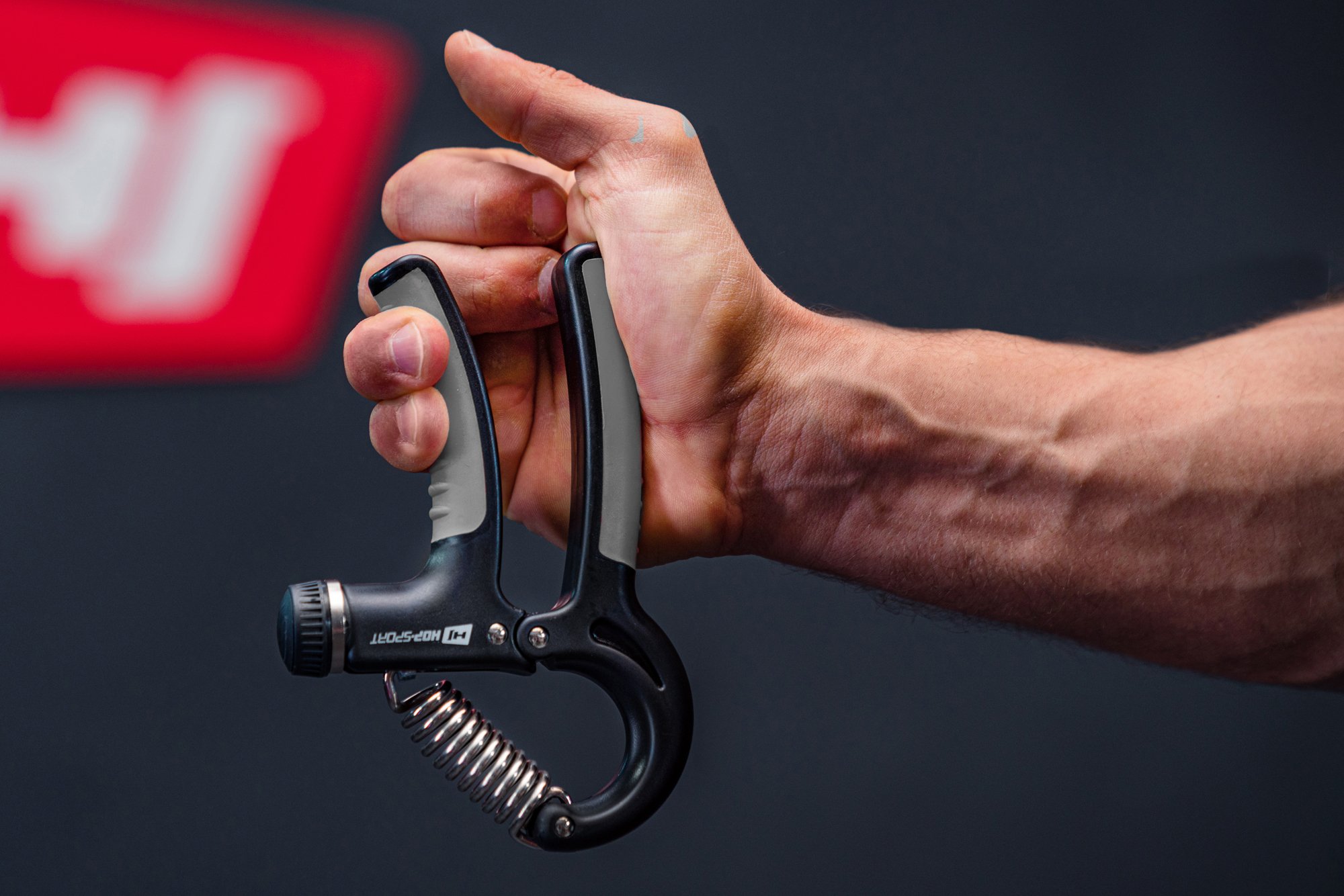 Hombre sosteniendo un apretador ajustable negro-gris con mangos antideslizantes