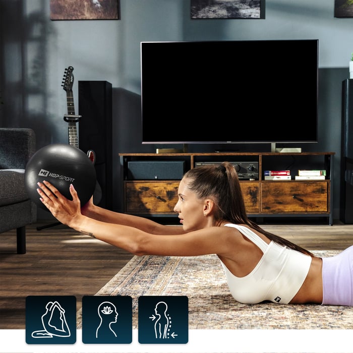 Modelo realizando elevaciones con una pelota negra de pilates Hop-Sport