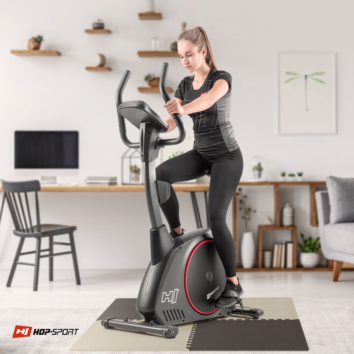 Chica ejercitándose en equipo de fitness que está sobre la estera puzzle marrón-beige de Hop-sport