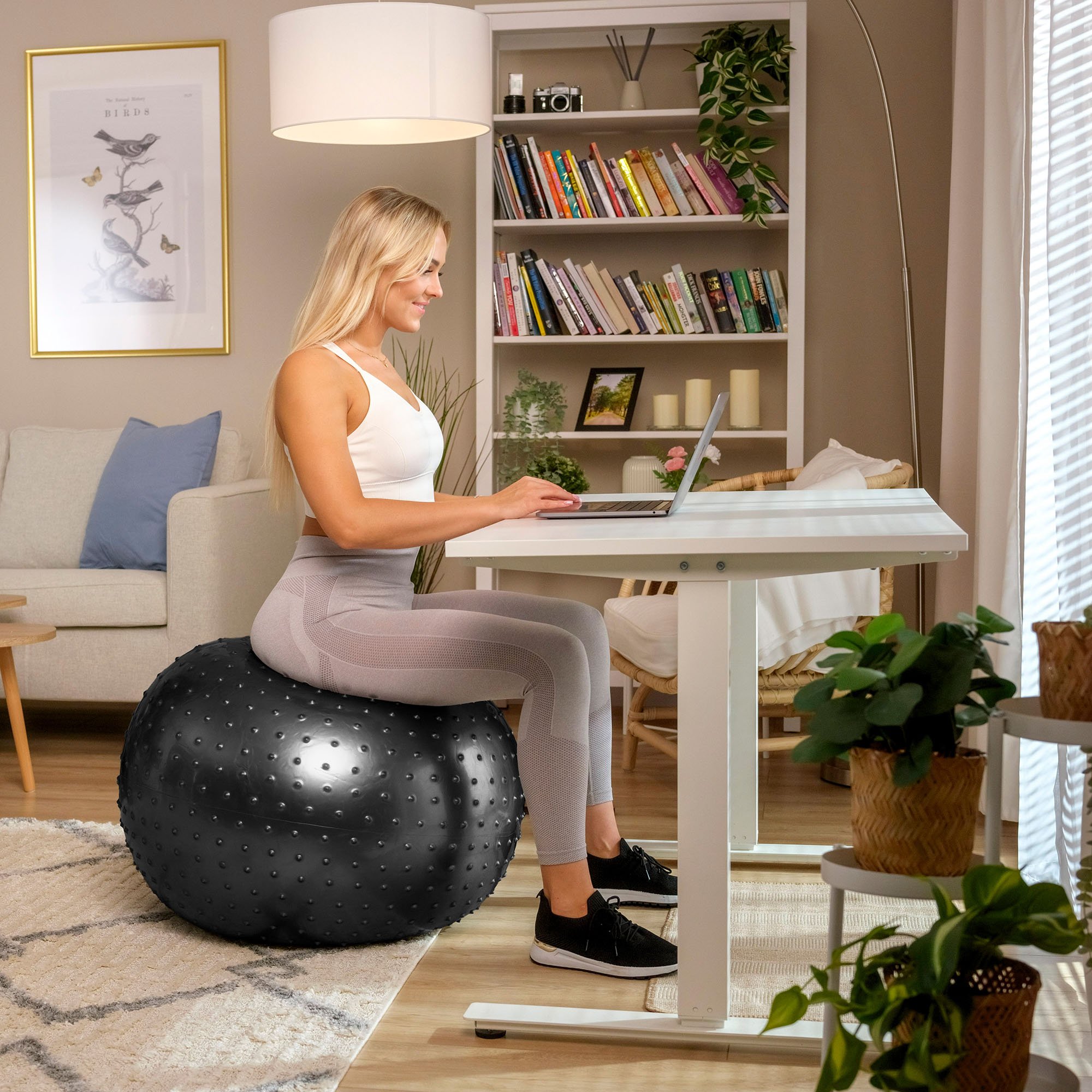 Mujer utiliza una pelota negra con protuberancias para trabajar en el escritorio